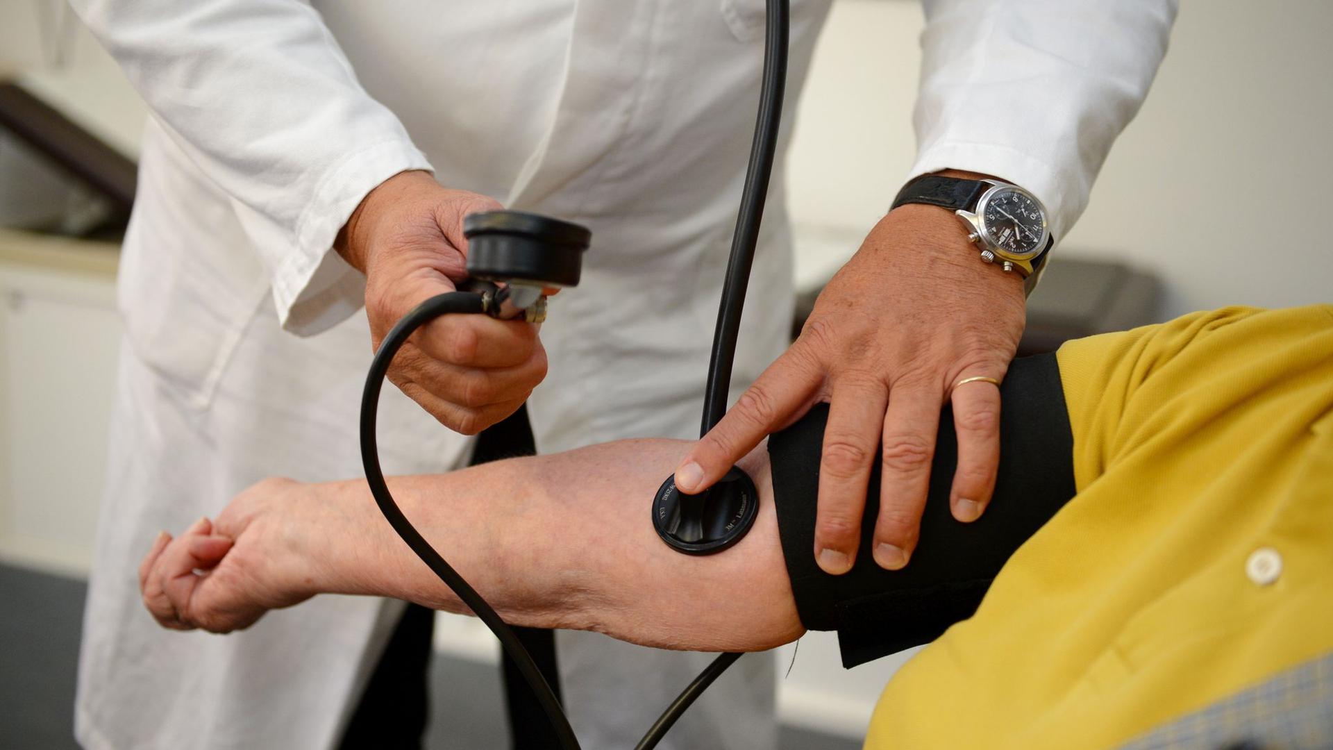 ein Arzt misst den Blutdruck einer Patientin