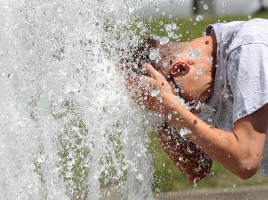 Bei Temperaturen um 29 Grad Celsius erfrischt sich ein junger Mann im Berliner Lustgarten am Wasser eines Brunnens.