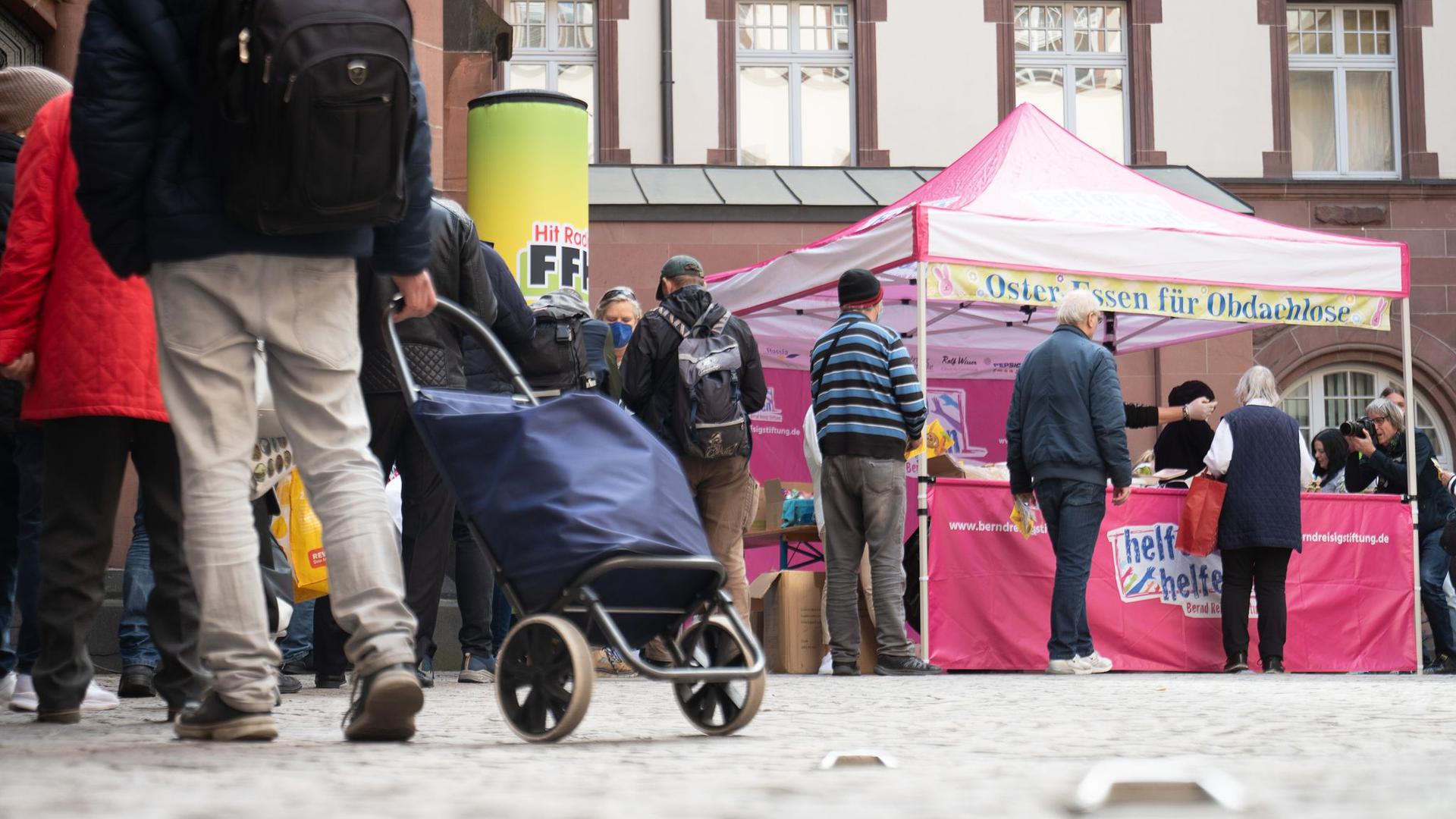 Menschen stehen bei der Ausgabe des Oster-Essens für Obdachlose der Bernd Reisig-Stiftung in Frankfurt an.
