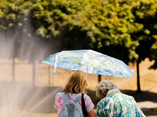 Zwei Frauen am Kölner Rheinufer mit Sonnenschirm.