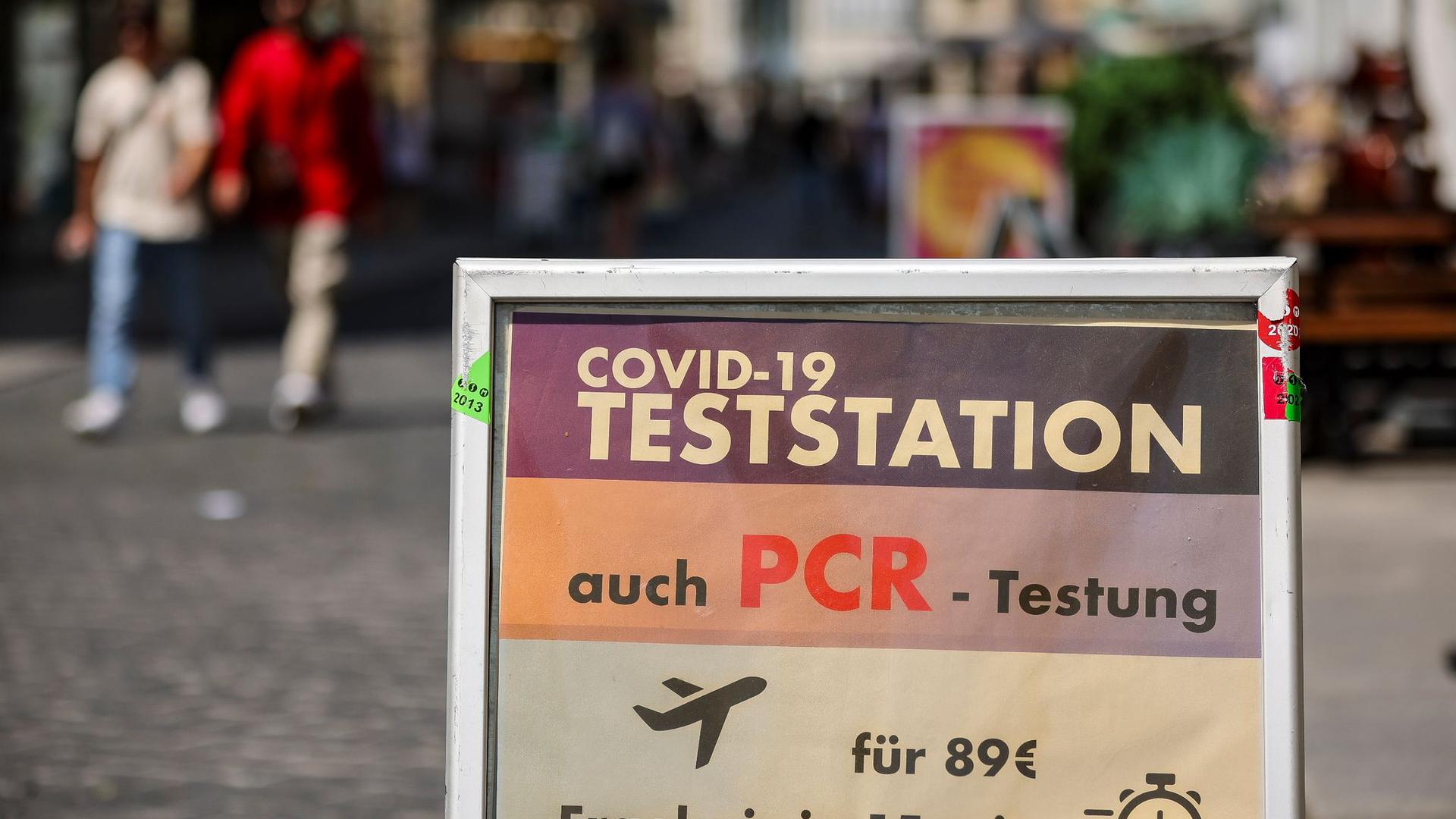 Ein Schild weist in der Innenstadt von Halle auf eine PCR-Teststation hin.