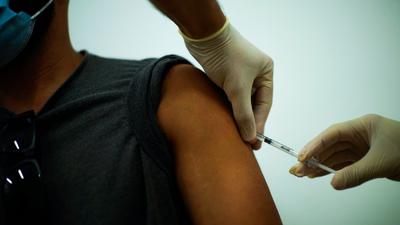 Ein Mann wird in einem medizinischen Zentrum in Barcelona von einem Arzt gegen Affenpocken geimpft.