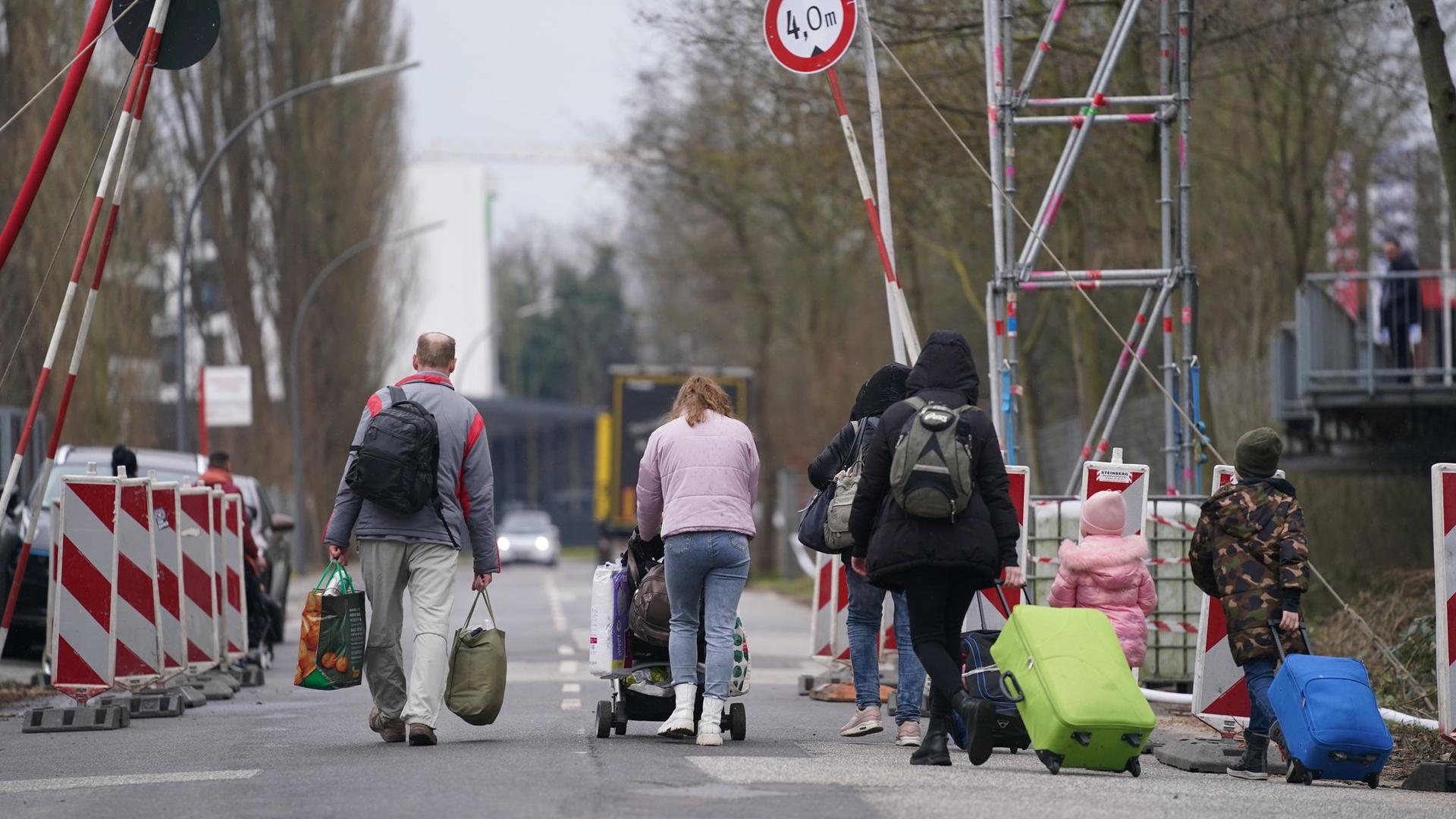 Aus der Ukraine geflüchtete Menschen verlassen mit ihrem Gepäck eine Unterkunft in Hamburg.