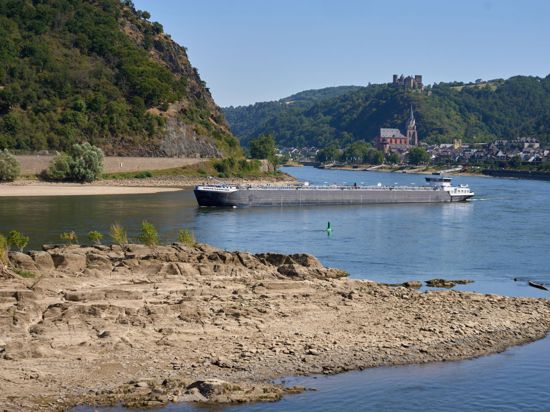 Ein Frachtschiff passiert auf dem Rhein einen Felsen. Durch die anhaltenden Trockenheit des Hochsommers fällt der Wasserspiegel des Mittelrheins immer weiter.