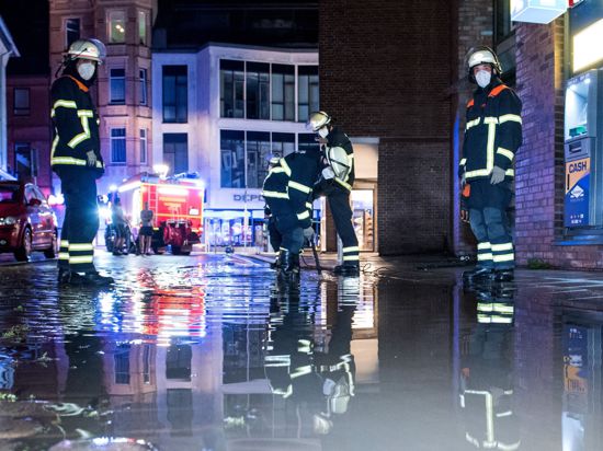 Feuerwehrleute pumpen in Hamburg Wasser von einer überfluteten Straße ab.