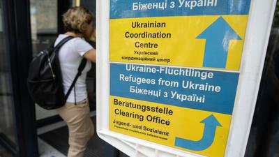 Eine Besucherin geht an einem Hinweisschild der Initiative Ukrainian Coordination Center im Amt für multikulturelle Angelegenheiten in Frankfurt am Main vorbei.