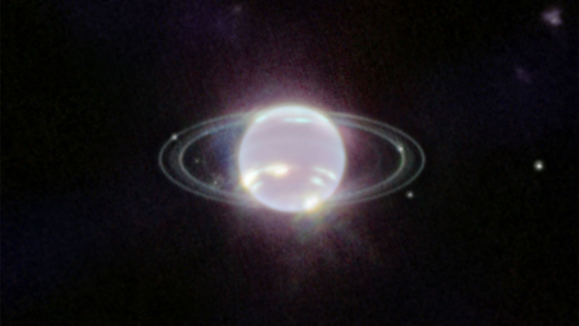Der Planet Neptun schwebt im Zentrum einiger Ringe. Die Ringe wurden durch den Einsatz der Nahinfrarotkamera (NIRCam) zum ersten Mal seit mehr als drei Jahrzehnten in vollem Fokus sichtbnar.