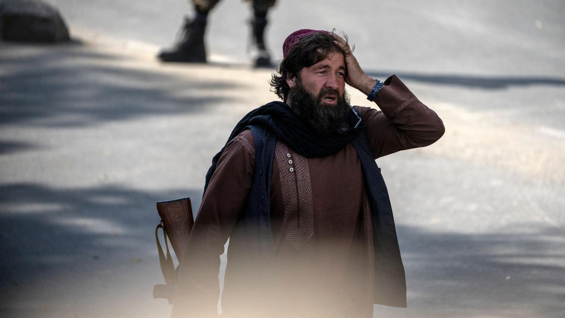 Ein Taliban-Kämpfer steht am Explosionsort und hält sich die Hand an den Kopf.