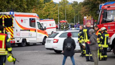 Einsatzkräfte der Feuerwehr und des Roten Kreuzes stehen nach einem Gasaustritt vor der Schule in Idstein