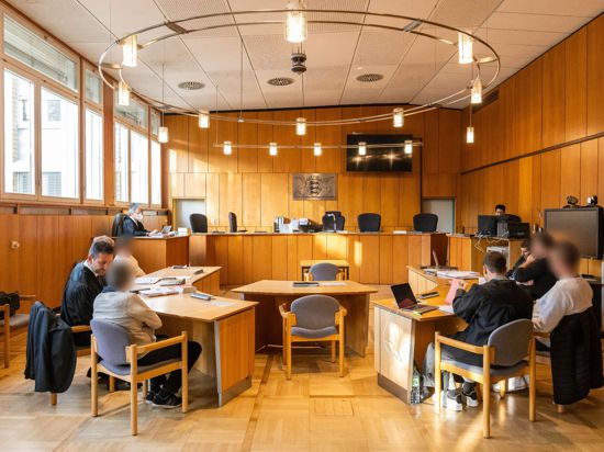 Vier Angeklagte sitzen mit ihren Verteidigern im Vorfeld der Verhandlung in einem Saal des Landgerichts Offenburg.