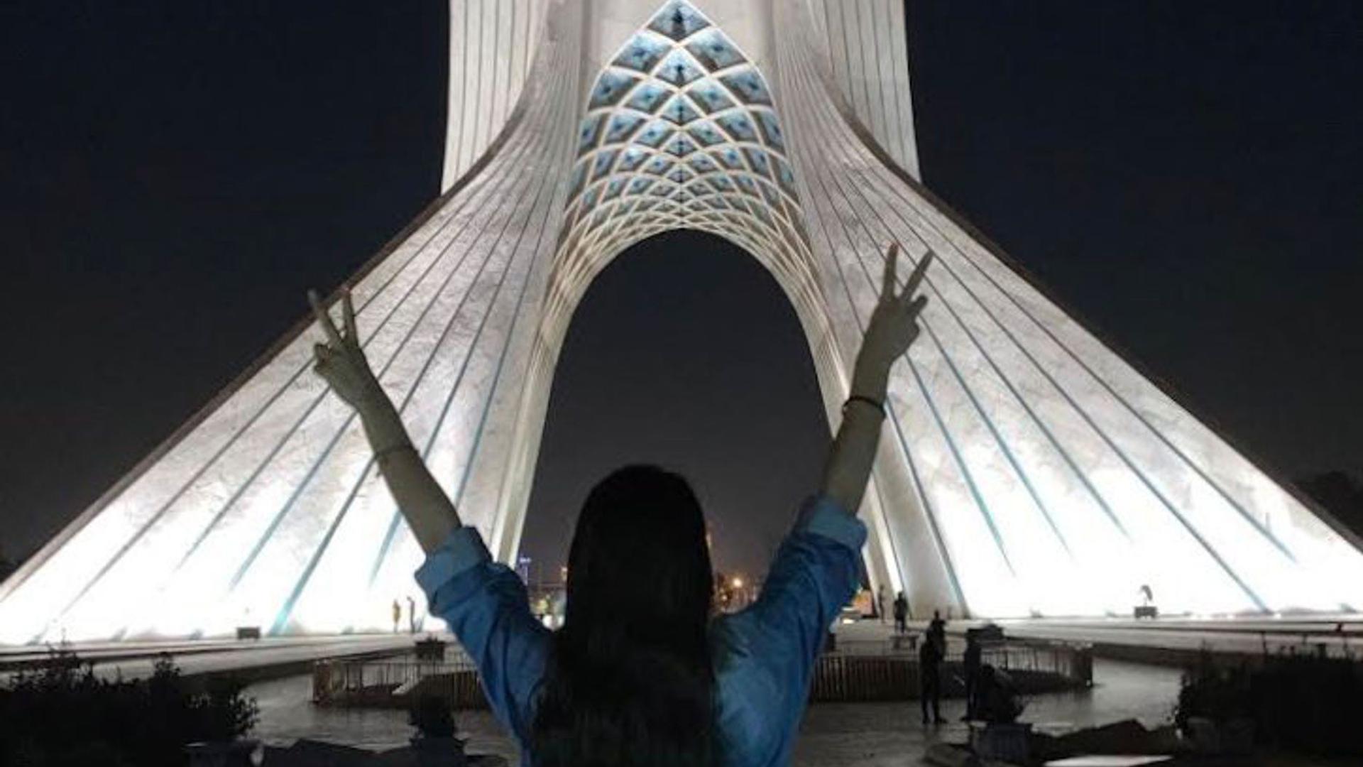 Ein Mädchen steht ohne das vorgeschriebene Kopftuch vor dem Azadi-Turm und zeigt mit beiden Händen das Victory-Zeichen. Bei landesweiten Protesten sind im Iran erneut viele Menschen getötet worden.