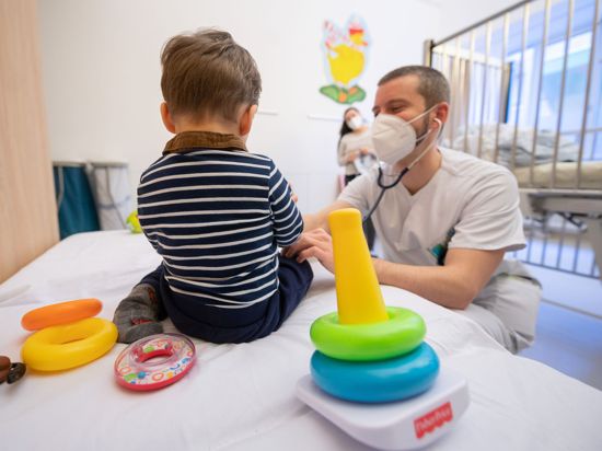 Ein Arzt untersucht in einer Kinderklinik ein Kind.