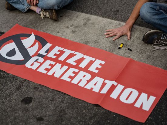 Ein Aktivist der Gruppe „Letzte Generation“ blockiert eine Kreuzung.