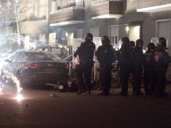 Polizeibeamte hinter explodierendem Feuerwerk in Berlin. Nach Angriffen auf Einsatzkräfte hat die Diskussion um Konsequenzen begonnen.