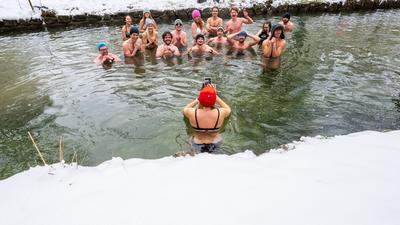 Mitglieder der Gruppe „Munich Hot Springs“ baden bei eisigen Temparaturen und Schneefall in einem Nebenarm des Eisbachs im Englischen Garten in München.