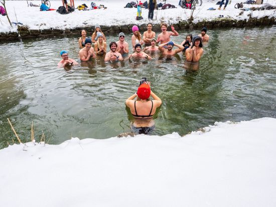 Mitglieder der Gruppe „Munich Hot Springs“ baden bei eisigen Temparaturen und Schneefall in einem Nebenarm des Eisbachs im Englischen Garten in München.