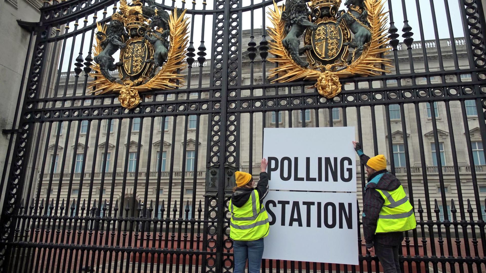 Anhänger der Kampagnengruppe Republic hängen ein Wahllokalschild ans Geländer des Buckingham Palace in London.