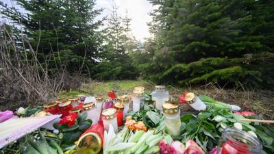 Blumen und Kerzen liegen an einer Tannenbaumschonung in Wunstorf. Nach der Tötung eines 14-jährigen Jungen sind die Hintergründe der Tat weiter unklar.