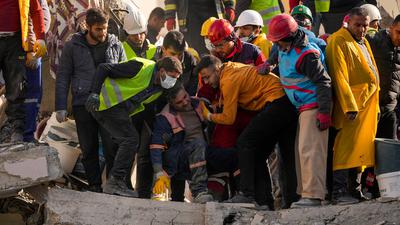 Ein Mitglied eines Rettungsteams wird in Adana von Teamkollegen getröstet, nachdem zwei Körper in einem zerstörten Gebäude gefunden wurden.
