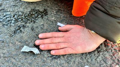 Eine Klimaaktivistin hat sich mit der Hand auf einer Hauptverkehrsstraße festgeklebt.