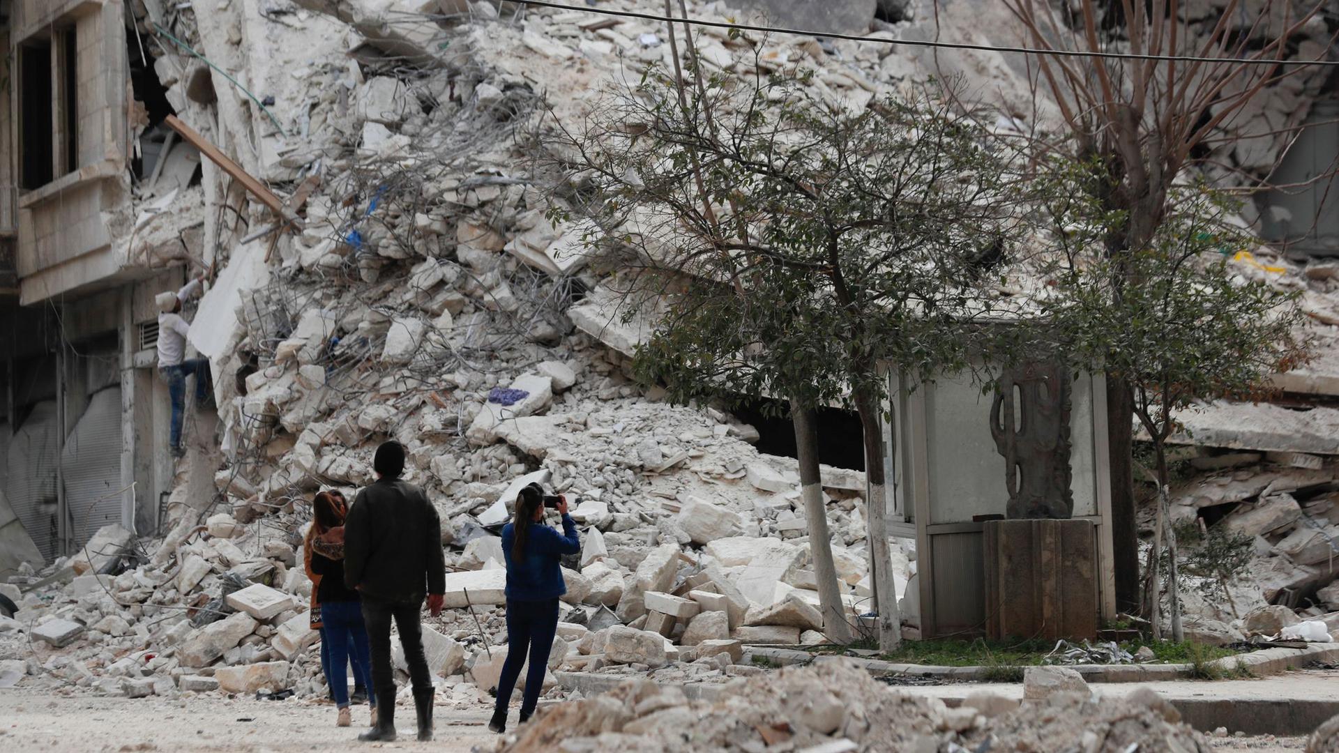 Menschen stehen vor den Trümmern eines Gebäudes, das bei dem jüngsten Erdbeben in Aleppo zerstört wurde.