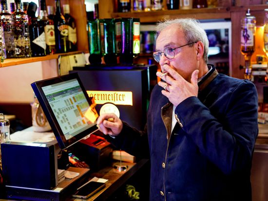 Peter Krall, Inhaber des „Hofbräu Raucher Stüberl“ in Hamburg, raucht am Tresen seines Lokals eine Zigarette.