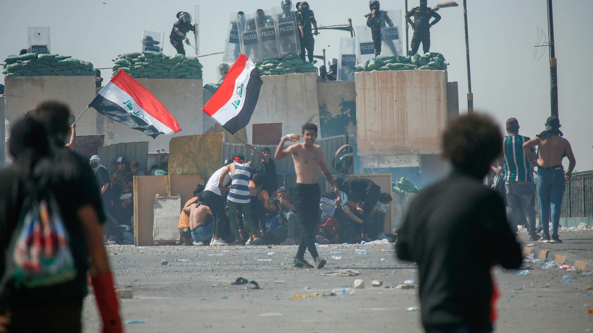 Regierungsgegner vor einer Barrikade der Polizei in Bagdad.