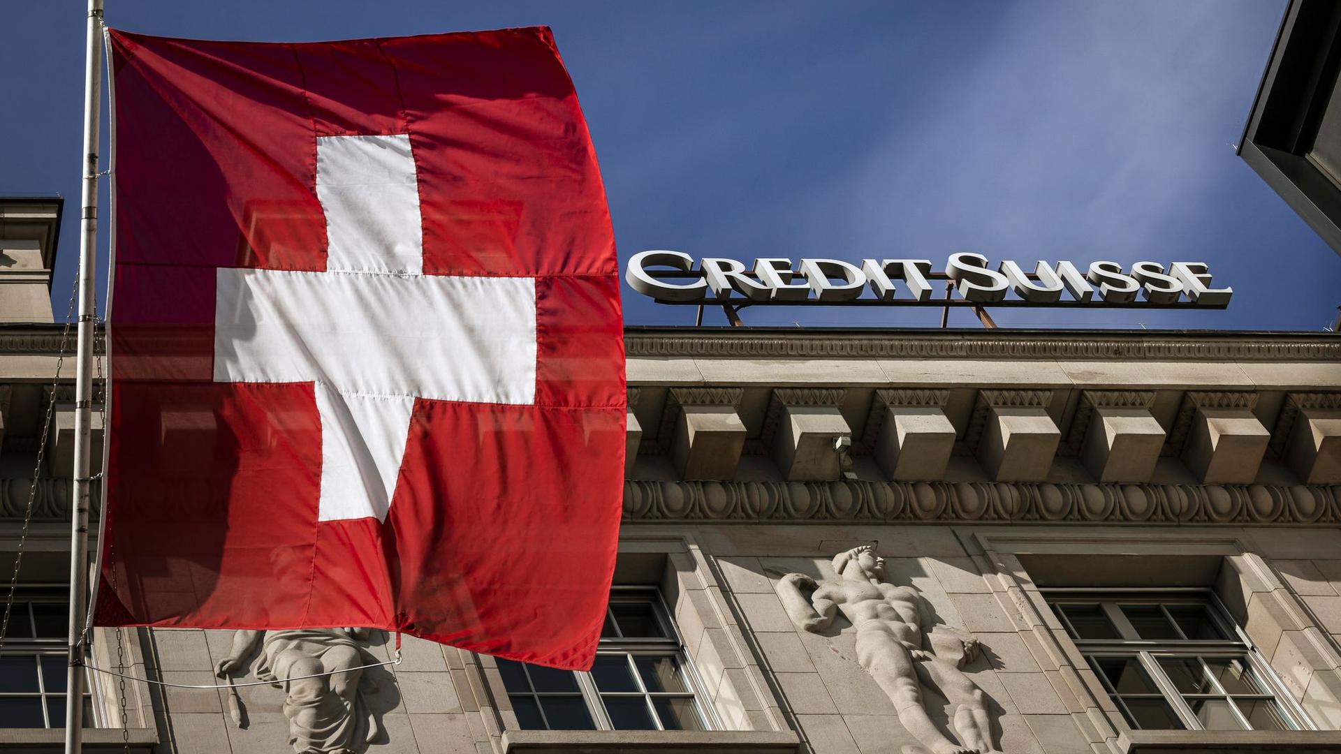 „Alle haben Angst vor dem Kollaps“: Die Flagge der Schweiz weht neben dem Logo der Schweizer Bank Credit Suisse in Luzern.