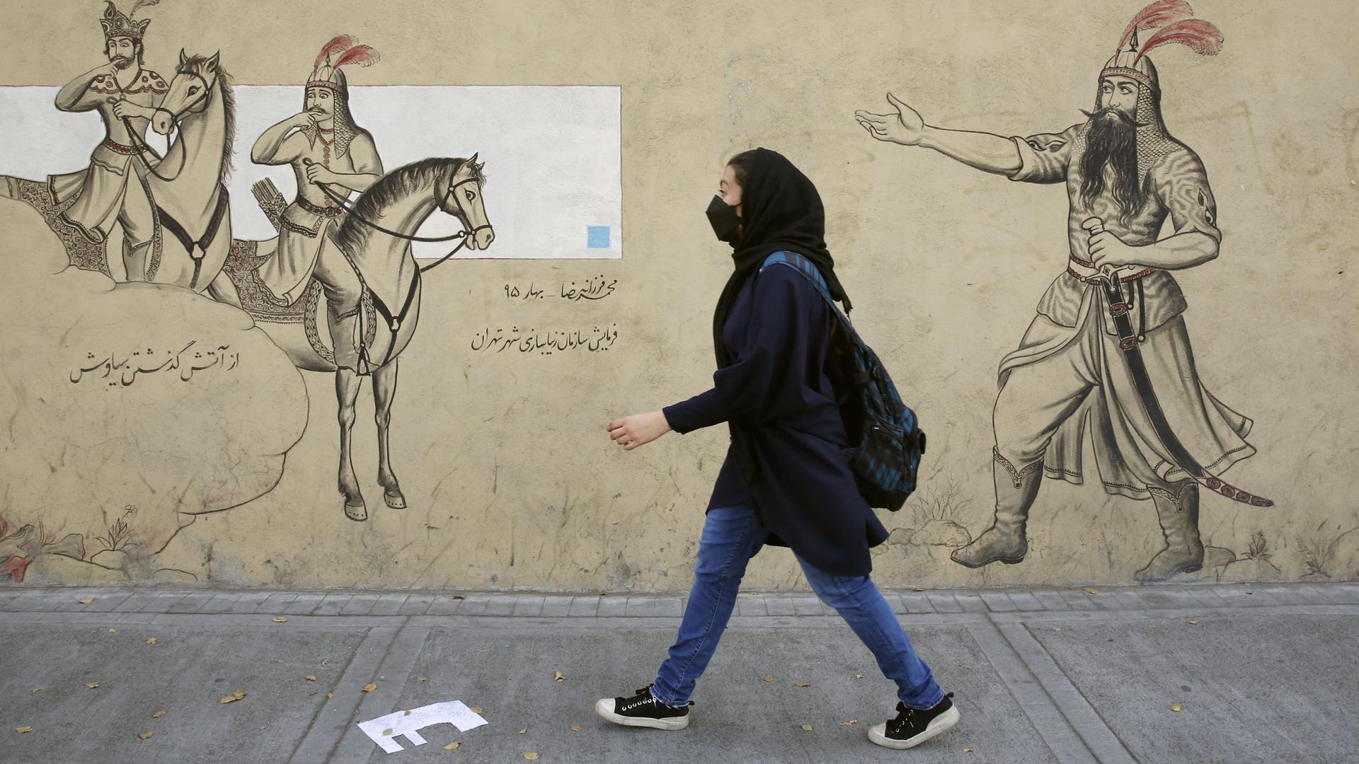 Ein Mädchen geht an einer Häuserfassade in Teheran entlang.