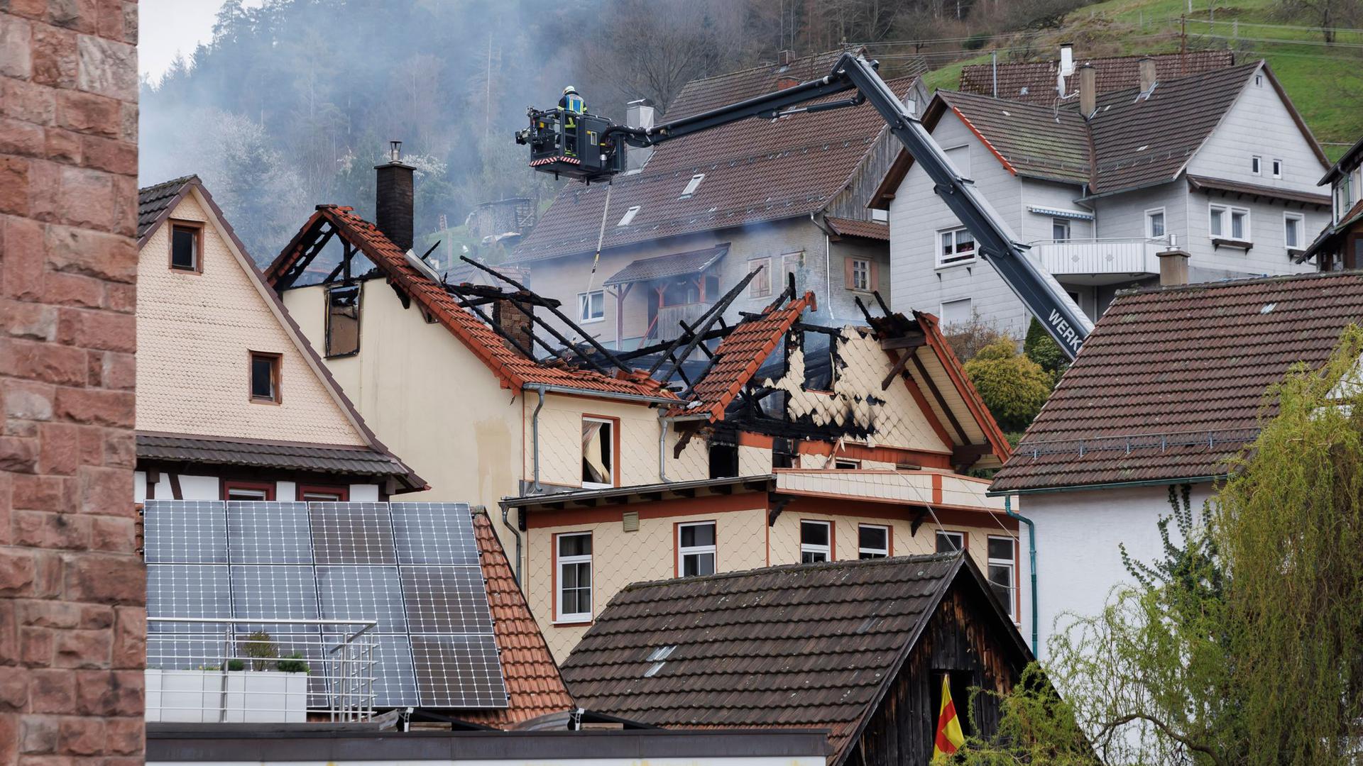 Mit einem Spezialfahrzeug werden Feuerwehrleute von oben in das abgebrannte Haus abgelassen.