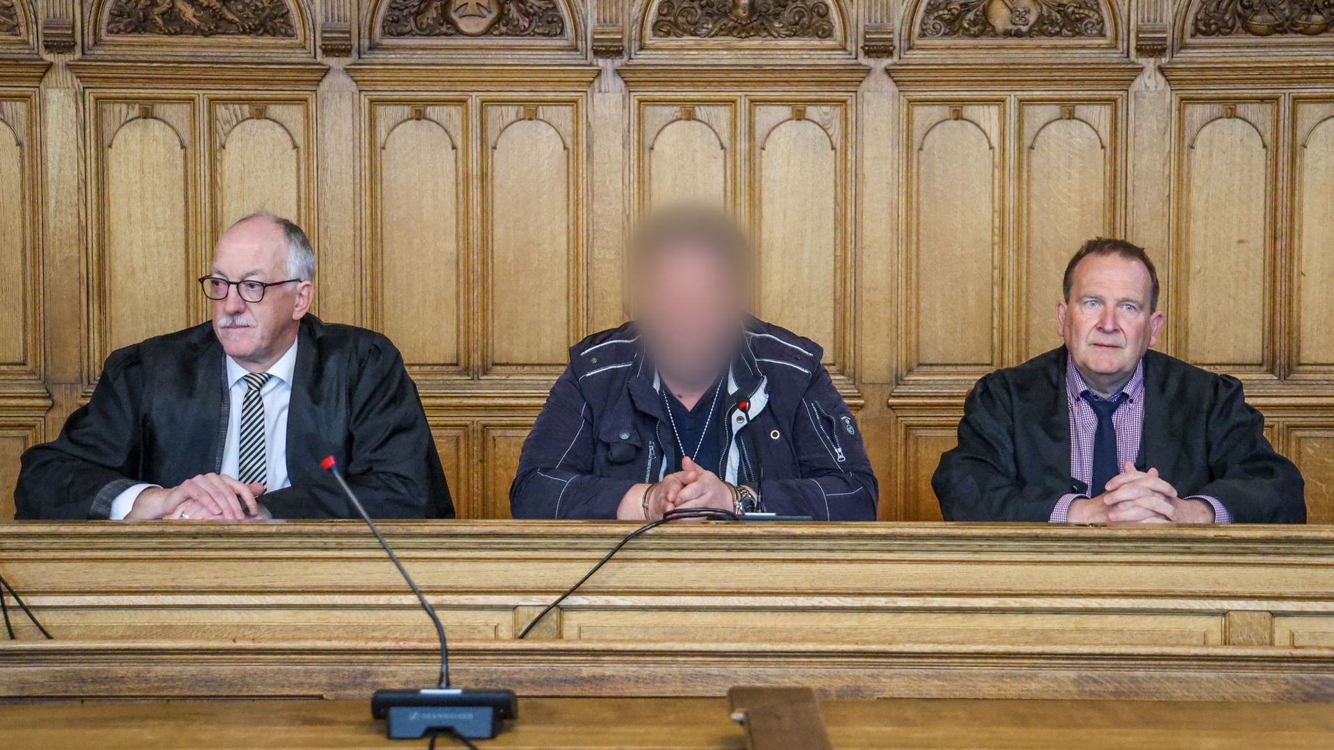 Der Angeklagte (M) sitzt vor der Urteilsverkündung im Prozess wegen Mordes im Landgericht Bremen zwischen seinen Verteidigern.