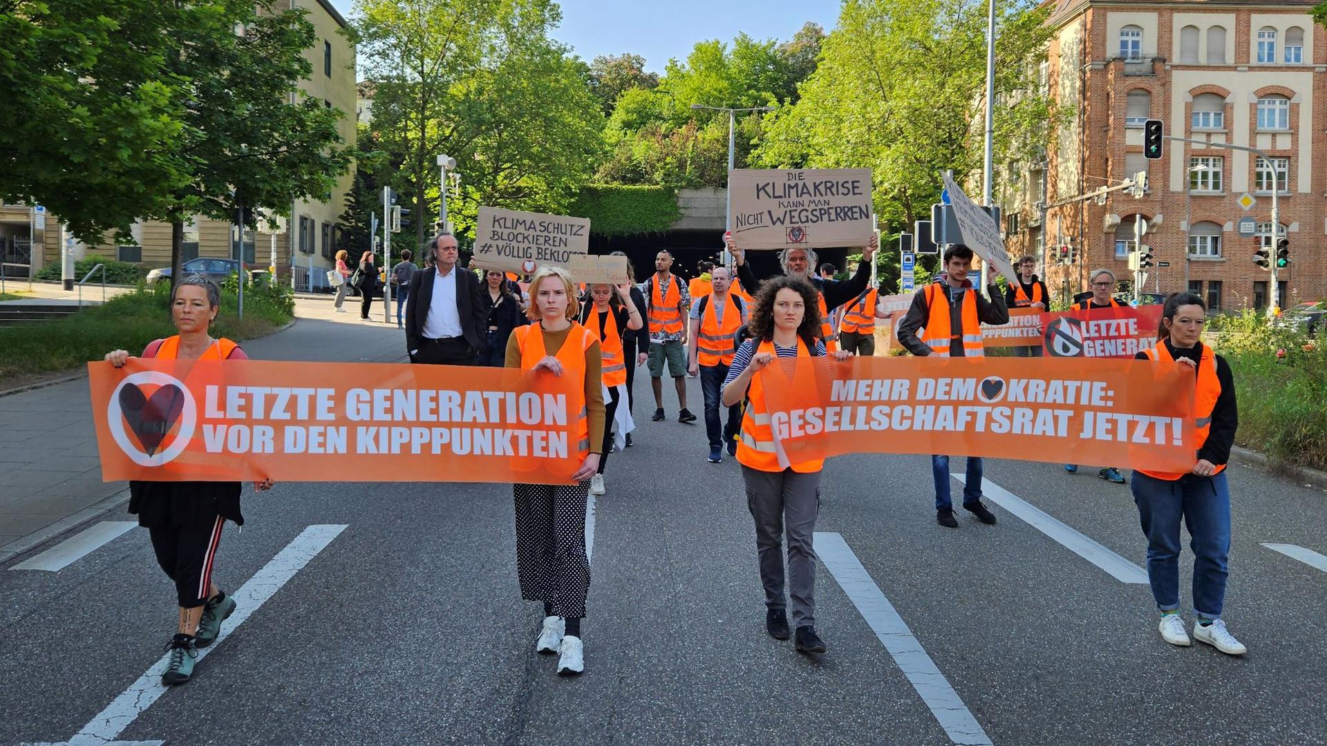Aktivistinnen und Unterstützer der Gruppierung Letzte Generation demonstrieren in Stuttgart mit Transparenten.