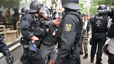 Polizisten halten einen Teilnehmer aus einer Demonstration in Leipzig fest.