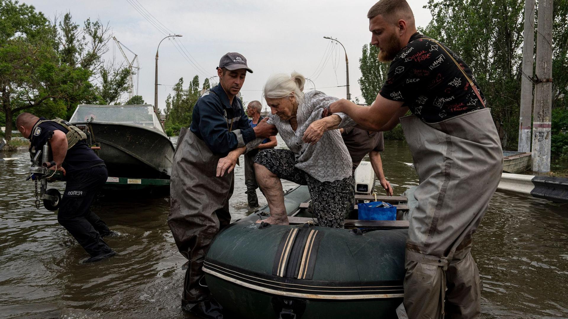 Rettungskräfte evakuieren eine ältere Frau aus einem überfluteten Viertel in Cherson.