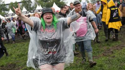 Metal-Fans laufen auf dem nassen Festivalgelände.