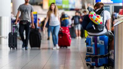 Ein junger Mann ruht sich auf seinem Koffer im Frankfurter Flughafen aus.