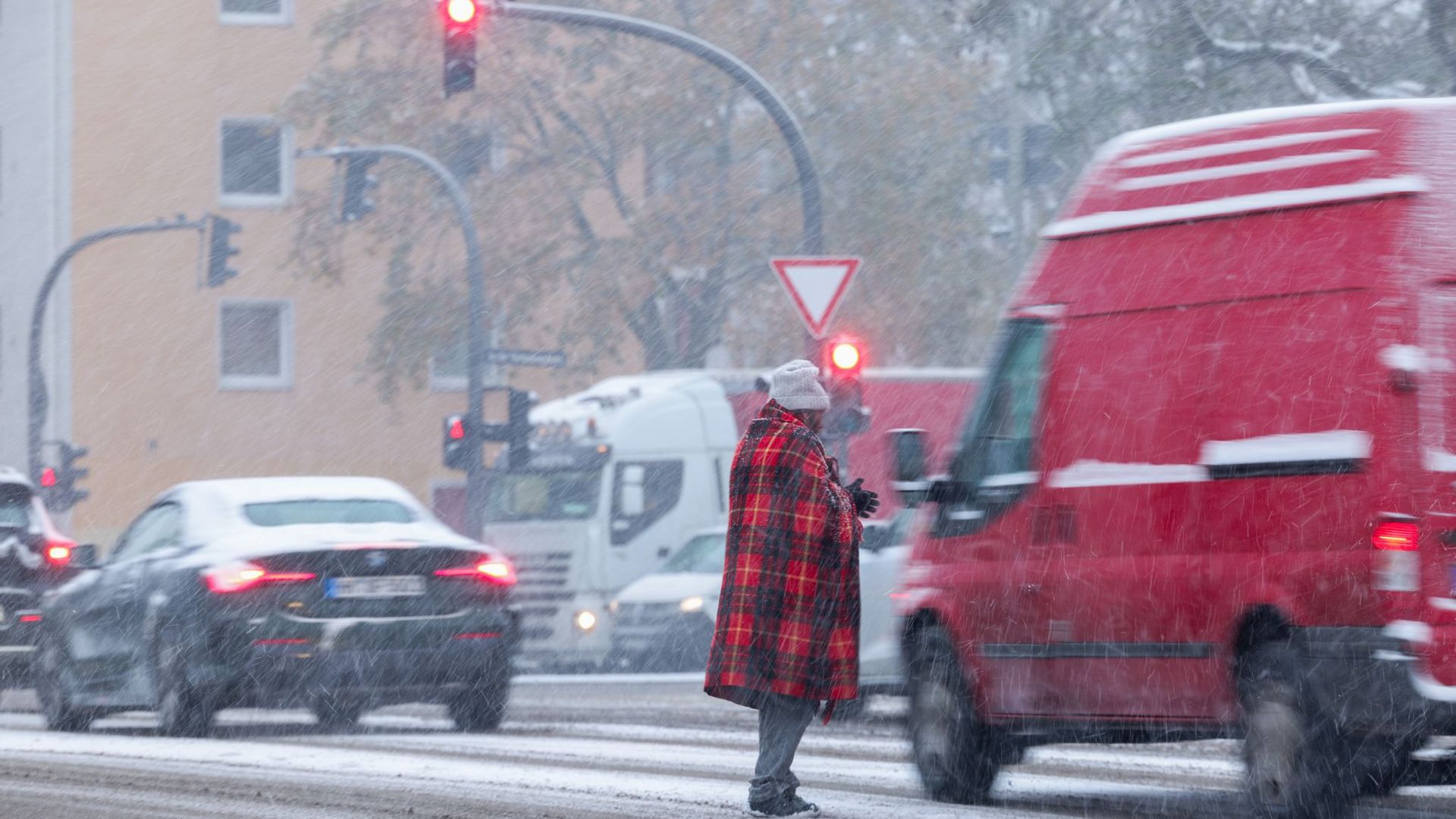 Zwischen wartenden Autos an der Ampfel: Bitten um Almosen bei Schneetreiben in Hamburg.
