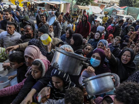 Vertriebene Palästinenser warten in Rafah, im Süden des Gazastreifens, auf Lebensmittel, die von palästinensischen Freiwilligen verteilt werden.
