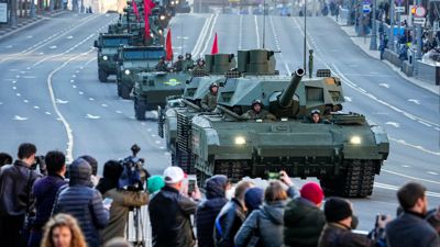 Zuschauer beobachten im Mai 2022, wie ein russischer T-14 Armata-Panzer (im Vordergrund) und andere gepanzerte Fahrzeuge auf der Twerskaja-Straße in Richtung Roter Platz rollen.