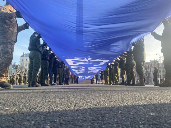 Ein riesige blaue Fahne mit der Aufschrift „Latvija Nato 20“ wird vor dem Freiheitsdenkmal entrollt. Lettland feiert 20 Jahre Nato-Mitgliedschaft.
