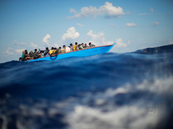 Menschen, die nach Europa wollen, sitzen in einem Holzboot im Mittelmeer. Symbolbild