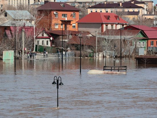 Anwohner stehen an einer Absperrung und beobachten ein überschwemmtes Gebiet im russischen Orenburg.