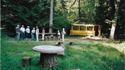 Personengruppe im Wald vor einer verlassenen Tram.