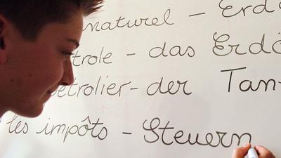 Der Schüler Franz schreibt deutsche und französische Vokabeln an eine Tafel. 