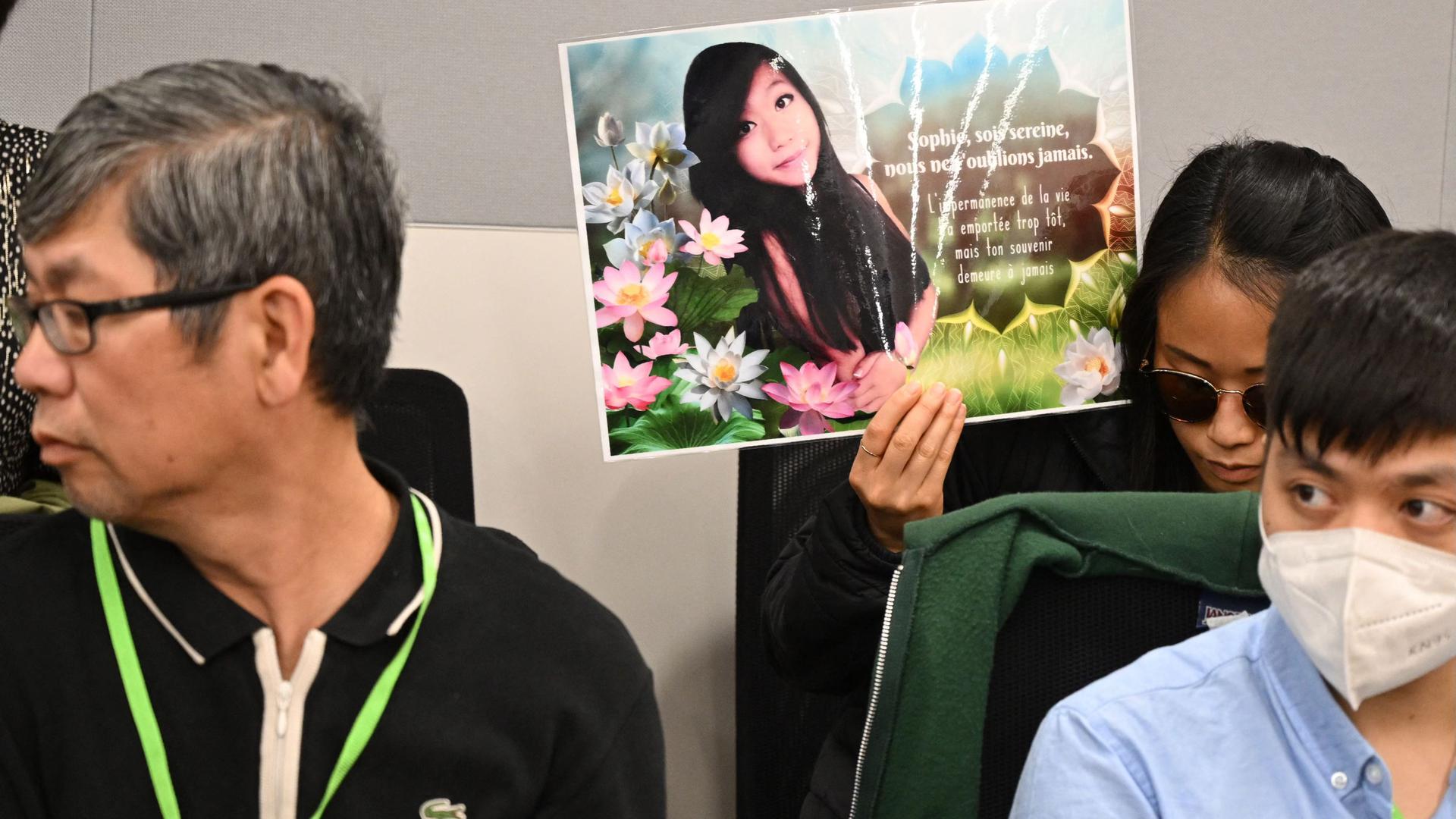 A relative of Sophie Le Tan holds a portrait in the courthouse of Strasbourg, eastern France, on June 27, 2022, ahead of the first day of Jean-Marc Reiser's trial, accused of murdering student Sophie Le Tan in 2018. (Photo by Frederick FLORIN / AFP)