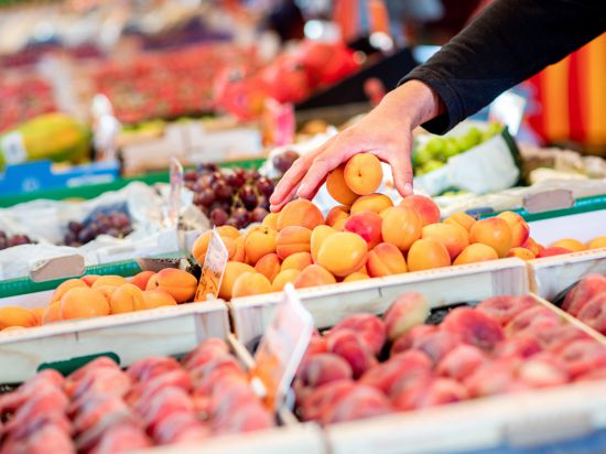 Ein Verkäufer greift an einem Obst- und Gemüsestand auf dem Wochenmarkt in eine Kiste mit Aprikosen. Die hohe Inflation ist einer Umfrage zufolge derzeit die größte Sorge der Menschen in Deutschland. (zu dpa «Umfrage: Inflation derzeit größte Sorge der Menschen in Deutschland») +++ dpa-Bildfunk +++