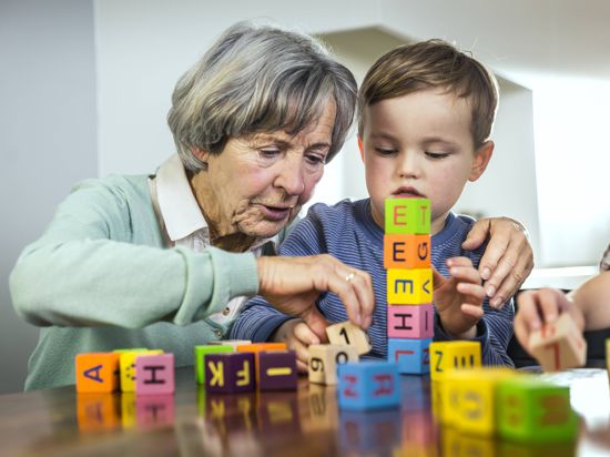 Grandmother helping grandson stacking toy blocks at home model released Symbolfoto property released AUF00646 