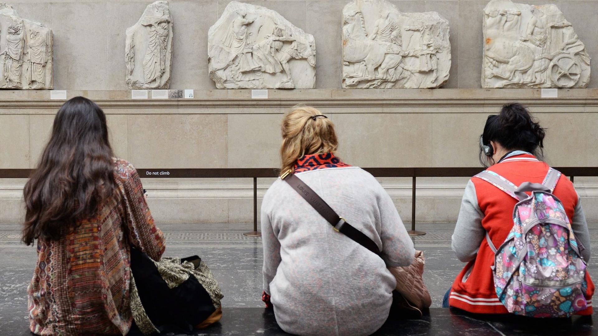 Besucher des British Museum in London sitzen vor Parthenon-Friesteilen.