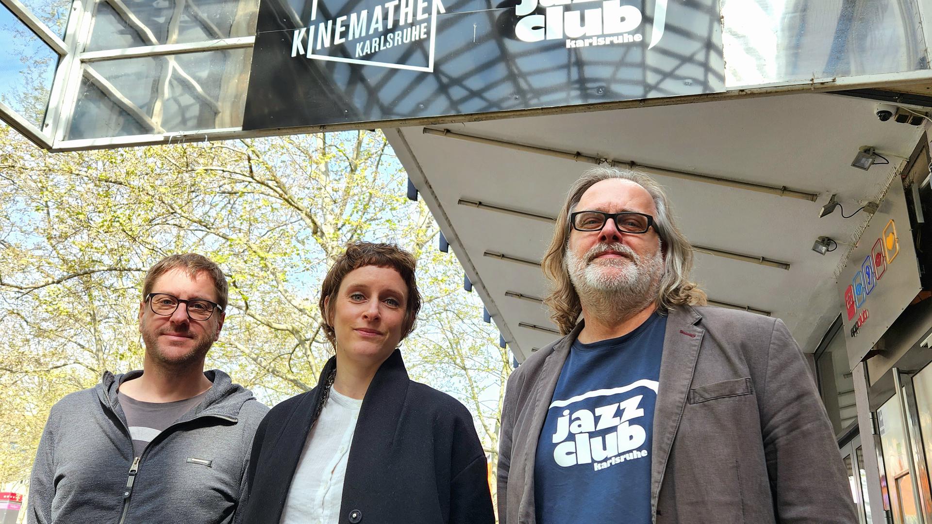 Niklas Braun, Julia Hildenbrand und Torsten Antoni vom Jazzclub Karlsruhe vor dem gemeinsamen Schild mit der Kinemathek in der Kaiserpassage. 
