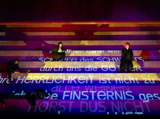 Szene der Oper „Elektra“ bei den Osterfestspielen 2024 in Baden-Baden mit projizierten Worten im Bühnenbild